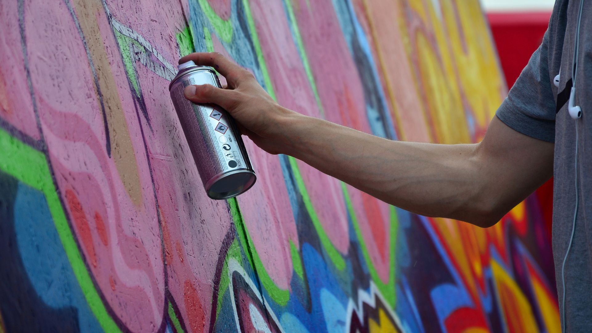 Graffiti-Sprayer Farbspraydose sprüht auf eine bunte Wand