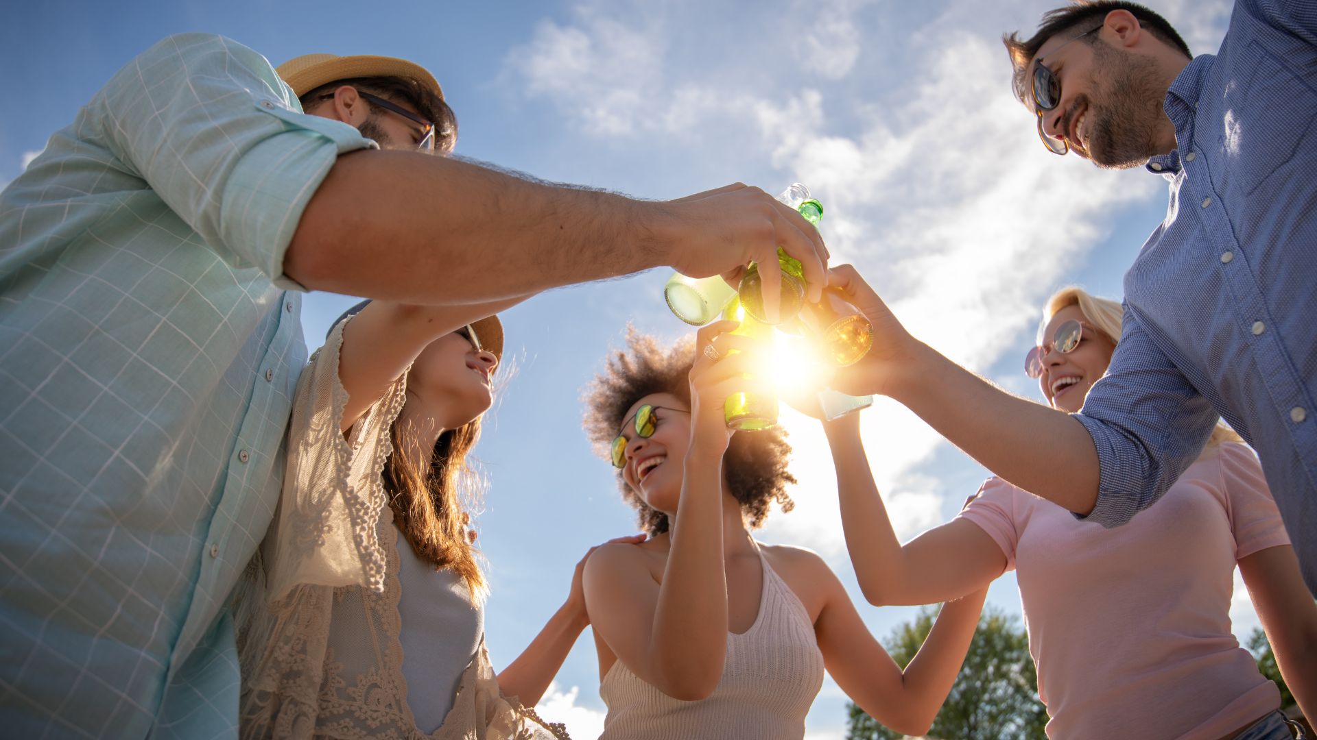 Eine Gruppe junge Menschen stoßen mit Getränken an und freuen sich