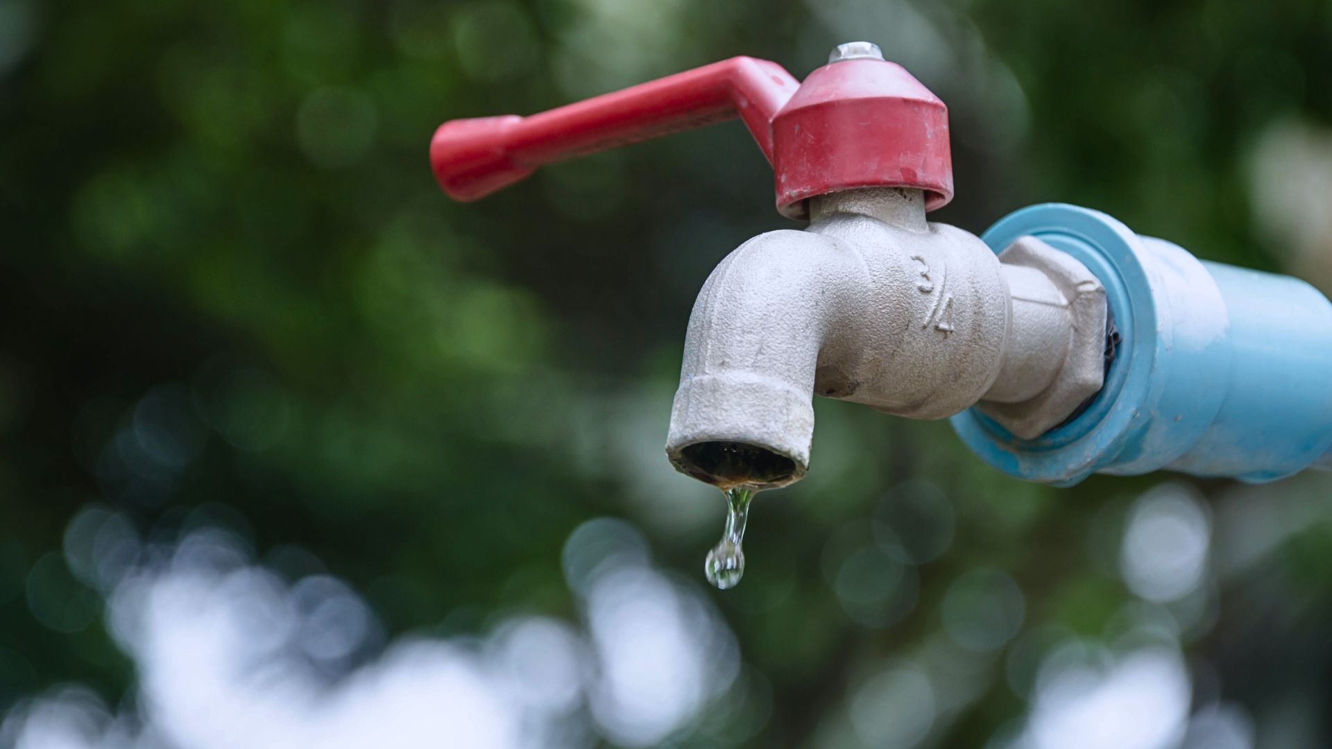 Wasserhahn mit einem Wassertropfen an einem Sommerlichen Tag mit einem rotem Hahn