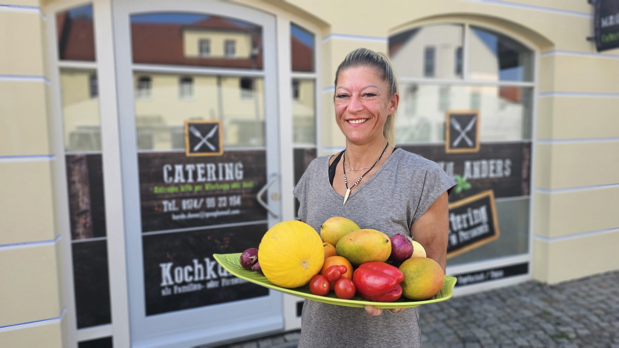 Dana Burde steht mit einem Teller Gemüse vor ihrem Kochstudio in Radebeul Altkötzschenbroda