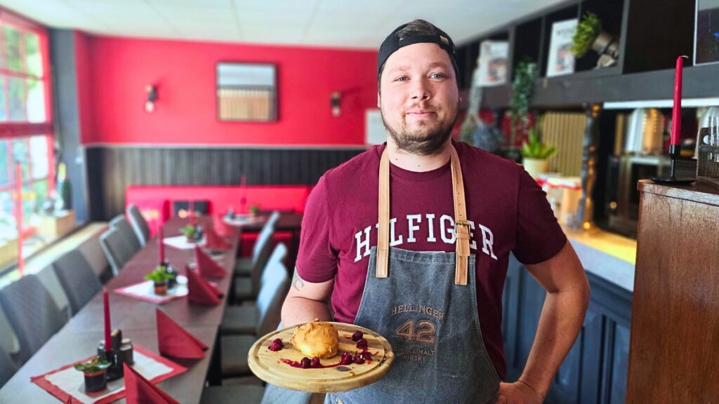 Robert Hentschel in seiner Robert's BBQ Lounge in Radebeul West er hält ein Gericht aus dem Podcast Messer und Gabel in der Hand