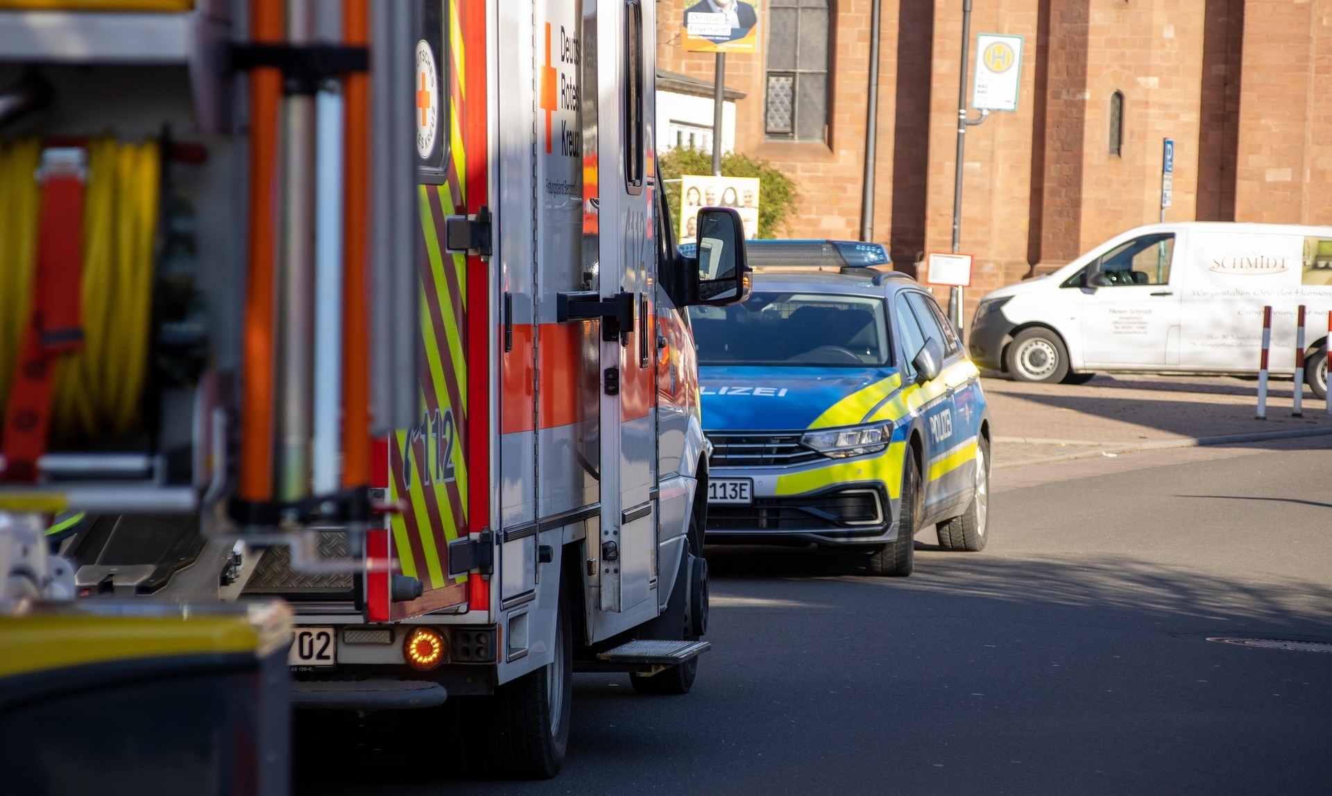 Polizei und Feuerwehr stehen am Straßenrand vor einer Bushaltestelle