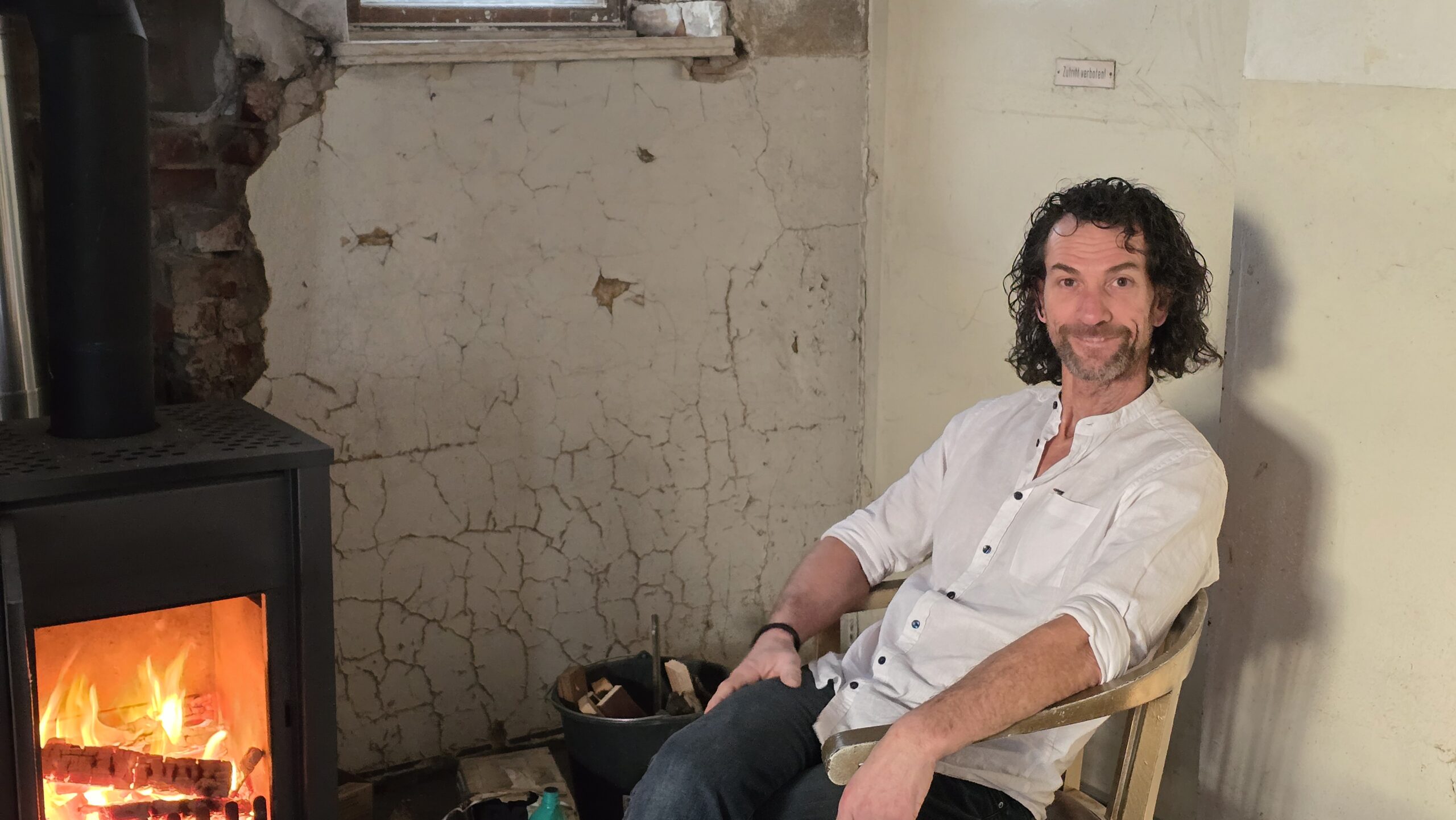 René Kuhnt sitzt zufrieden am Kamin. Noch ist der ein Provisorium, was viel wichtiger ist - der Schornstein ist original restauriert. Foto: © Branczeisz