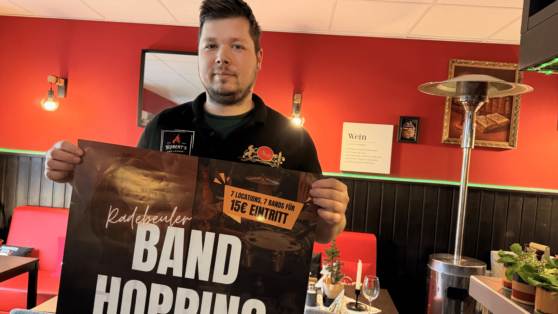 Robert Hentschel steht in seiner BBQ Lounge mit einem Band Hopping Plakat - Foto © Radebeul Aktuell (PS)