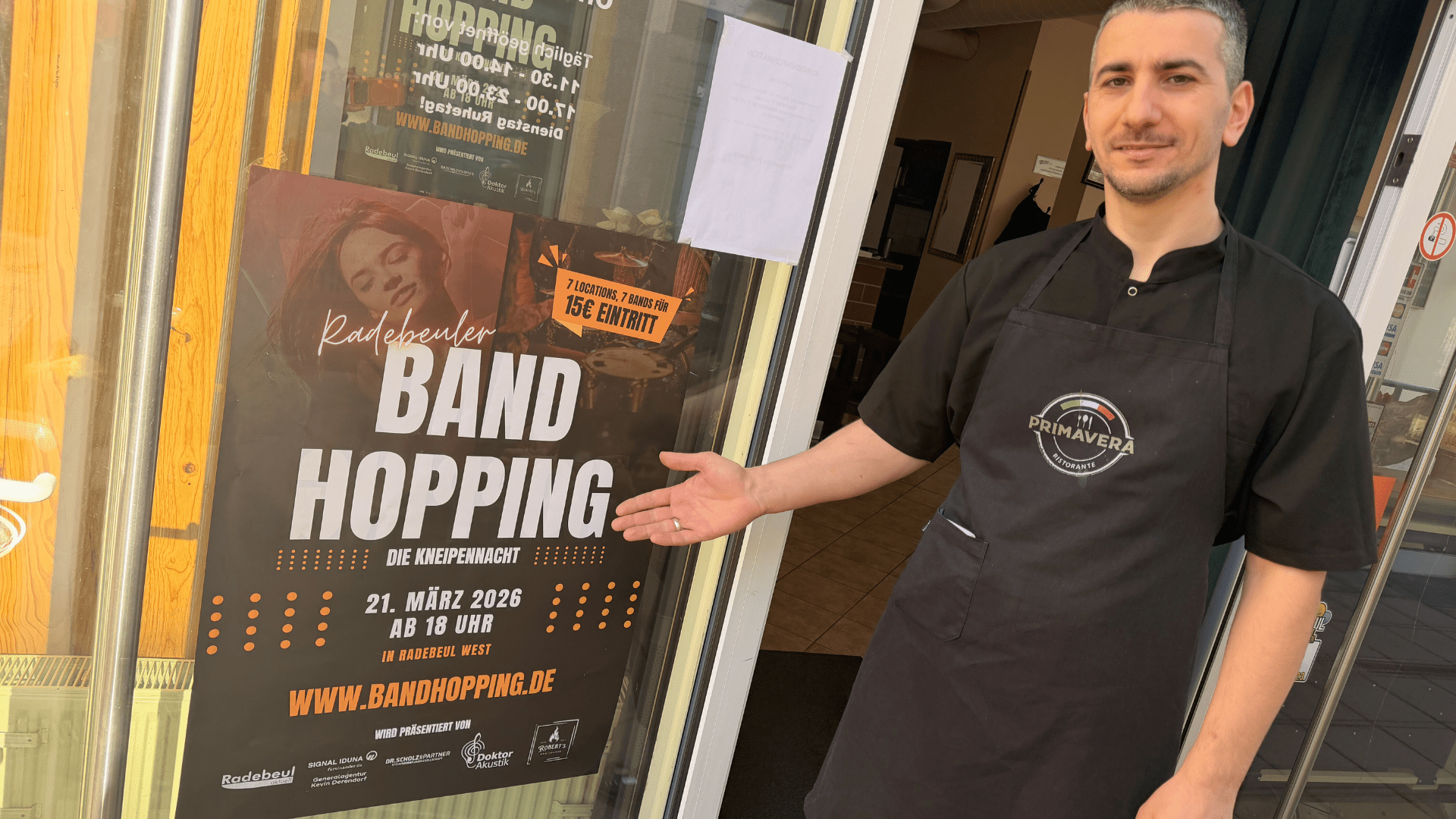 Inhaber Vito vor seinem Primavera in Radebeul Bahnhofstraße mit dem Band Hopping Plakat Foto © Radebeul Aktuell