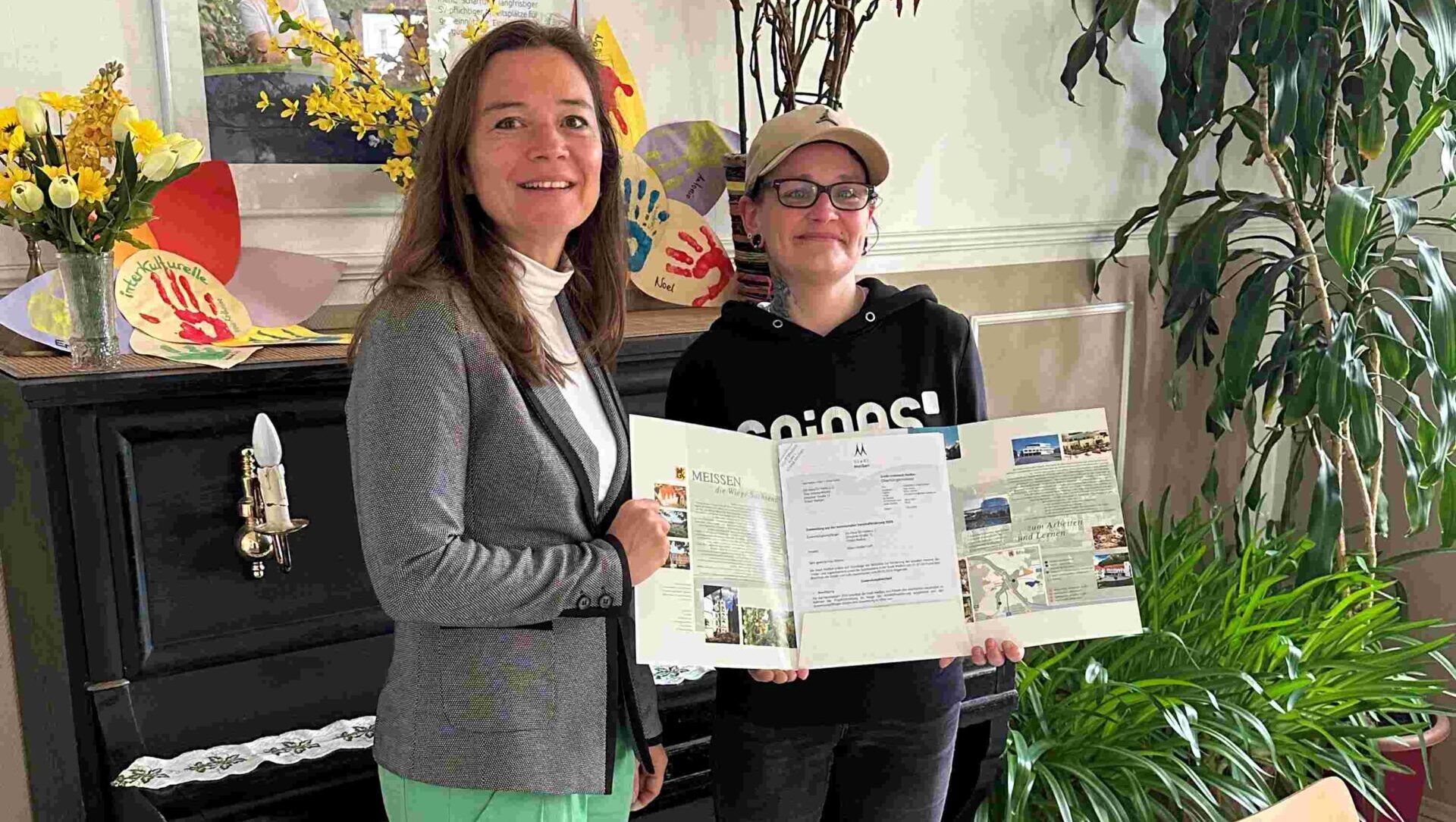 Katrin Nestler (l.) übergibt den Fördermittelbescheid an Mitarbeiterin Romy Leutert im Haus für Vieles. Foto © Stadt Meißen