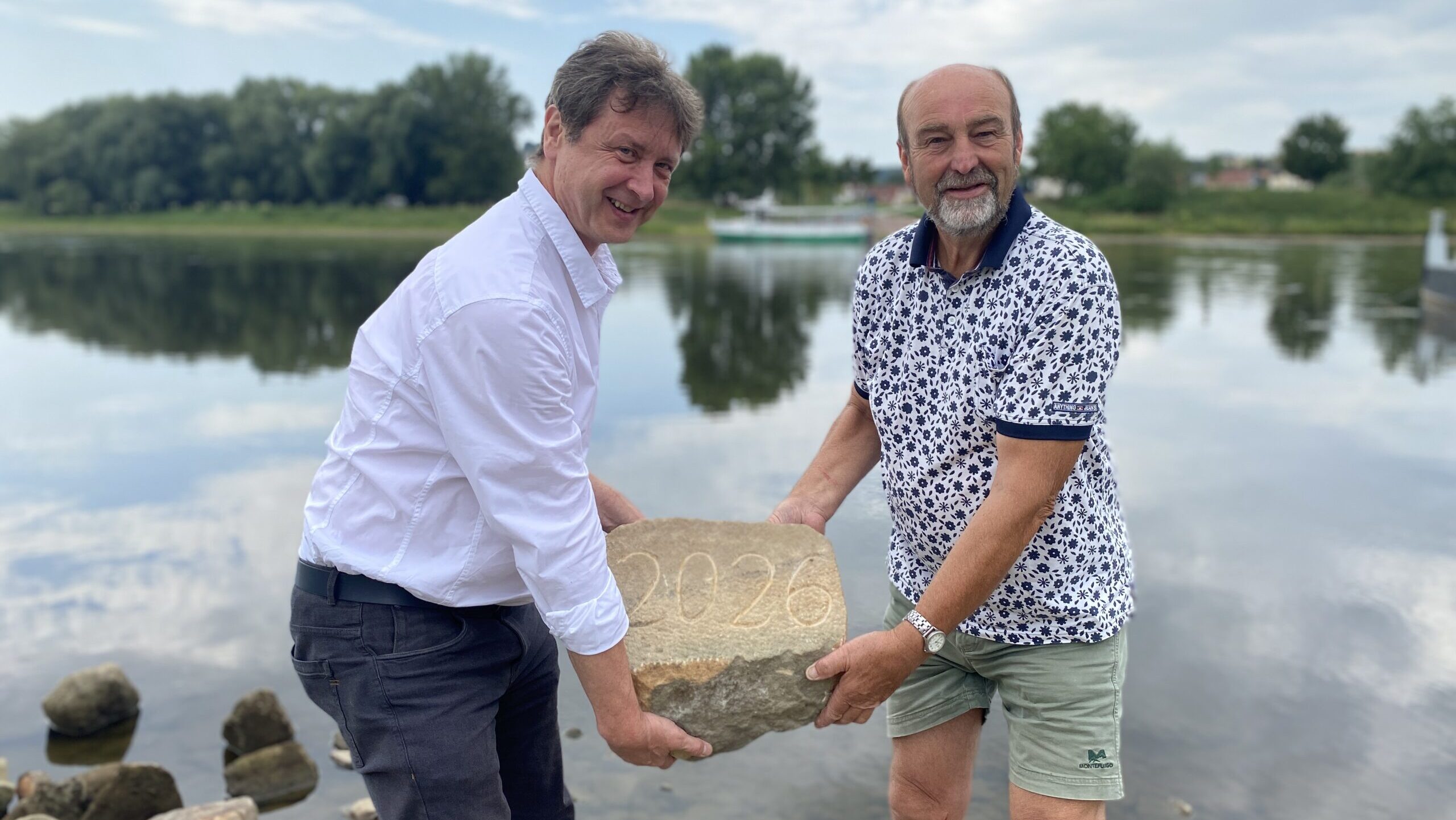 v. l.: Olaf Lier, Leiter des Fachbereichs Ordnungswesen, und Steffen Spindler, ehemaliger Lehrer, heben den Hungerstein in die Elbe. Foto © Coswig